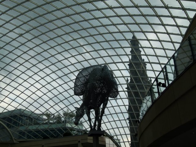 Cityscape of panelled glass roof, with sculpture made of fragments, modern penthouse and old church